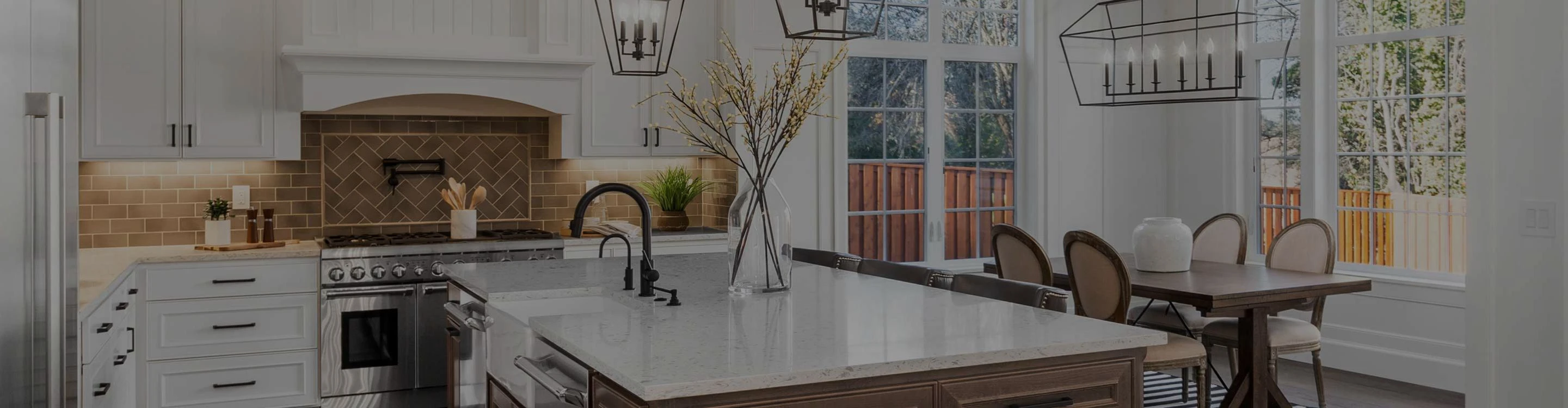 Modern kitchen showcasing a warm-toned herringbone backsplash tile, white cabinetry, a professional-grade stainless steel range, and a contrasting dark wood island with a farmhouse sink.